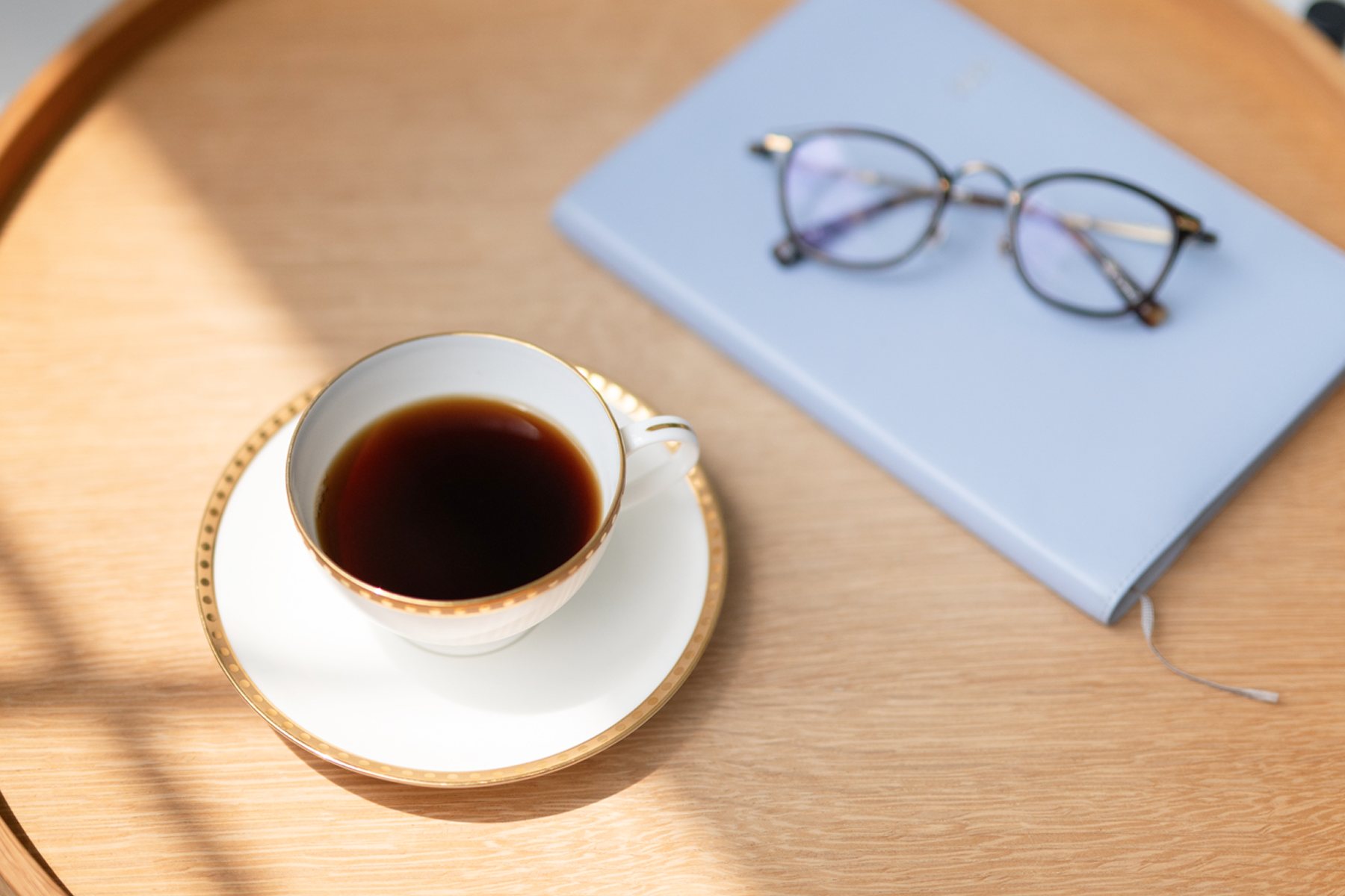 コーヒーとノート、めがねの置かれたテーブル